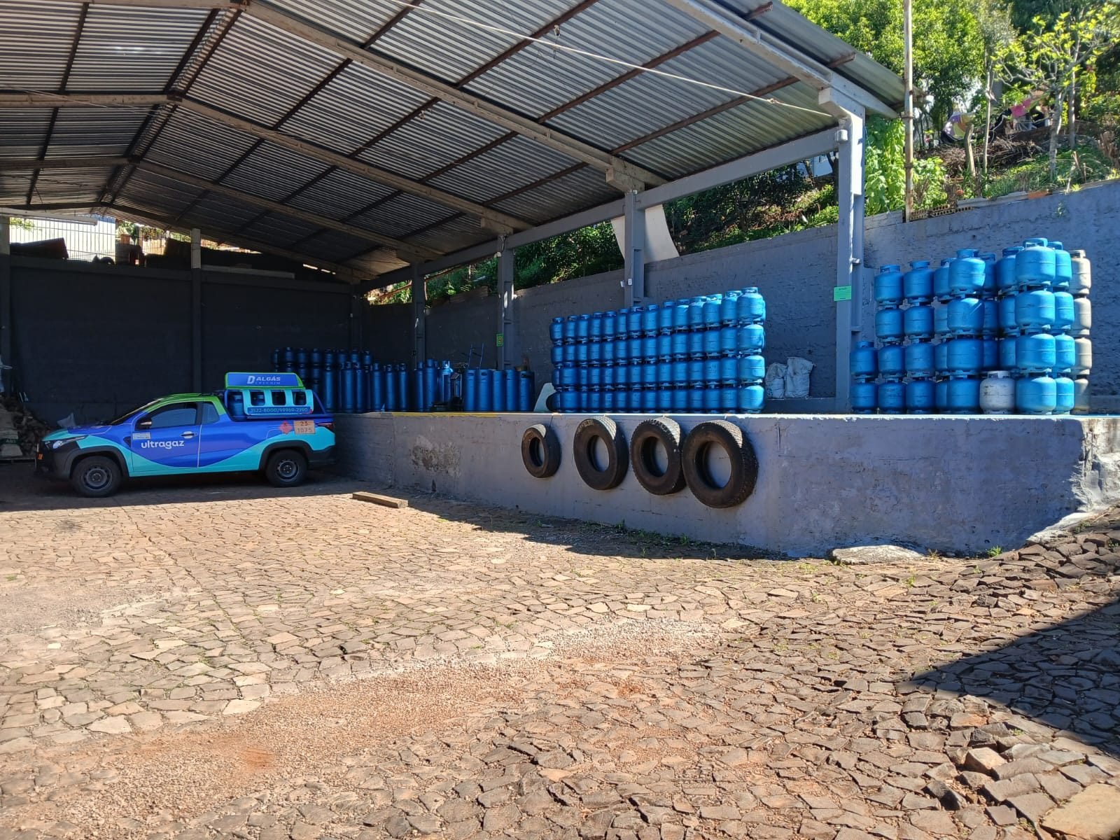 Pátio coberto da Dalgas Ultragaz com botijões empilhados e caminhonete de entrega